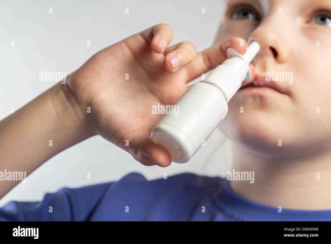 A girl sprays a spray against runny nose and nasal congestion into her