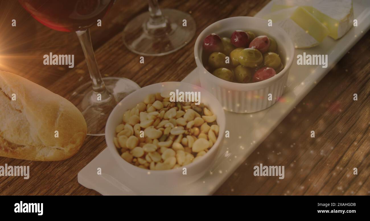 Image of lights over wine and snacks arrangement on wooden table Stock Photo