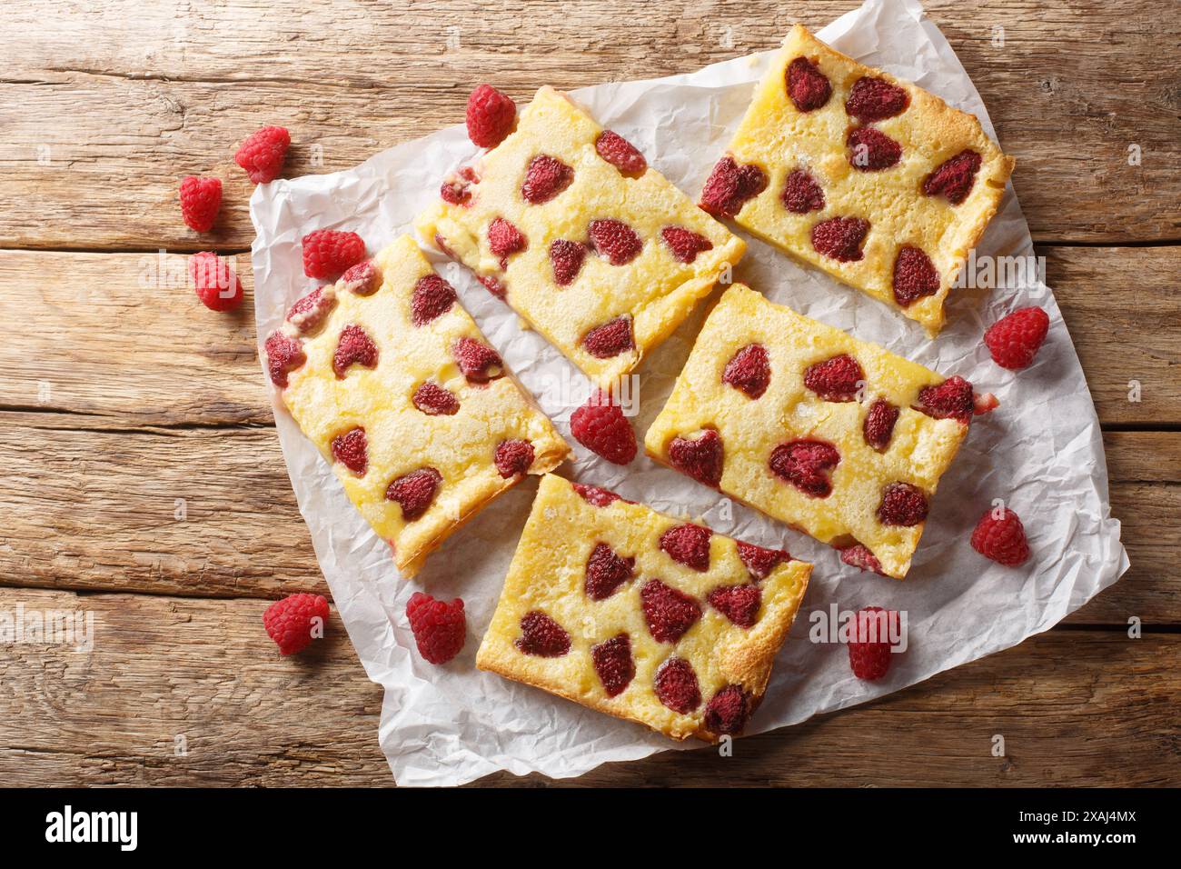 Sweet custard pie tart with fresh berry raspberries closeup on the paper on the wooden table. Horizontal top view from above Stock Photo