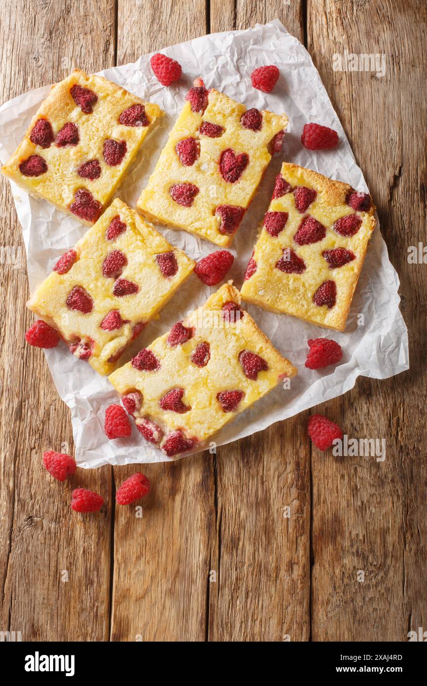 Homemade German berry pie with raspberry and custard closeup on the paper on the wooden table. Vertical top view from above Stock Photo