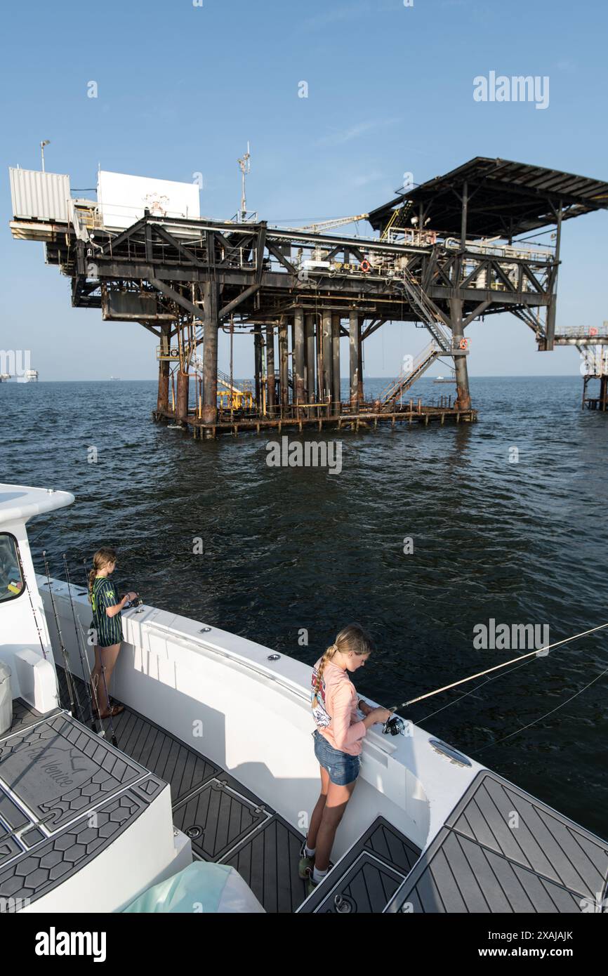 Anglers fish for baitfish while surrounded by offshore oil platforms in ...