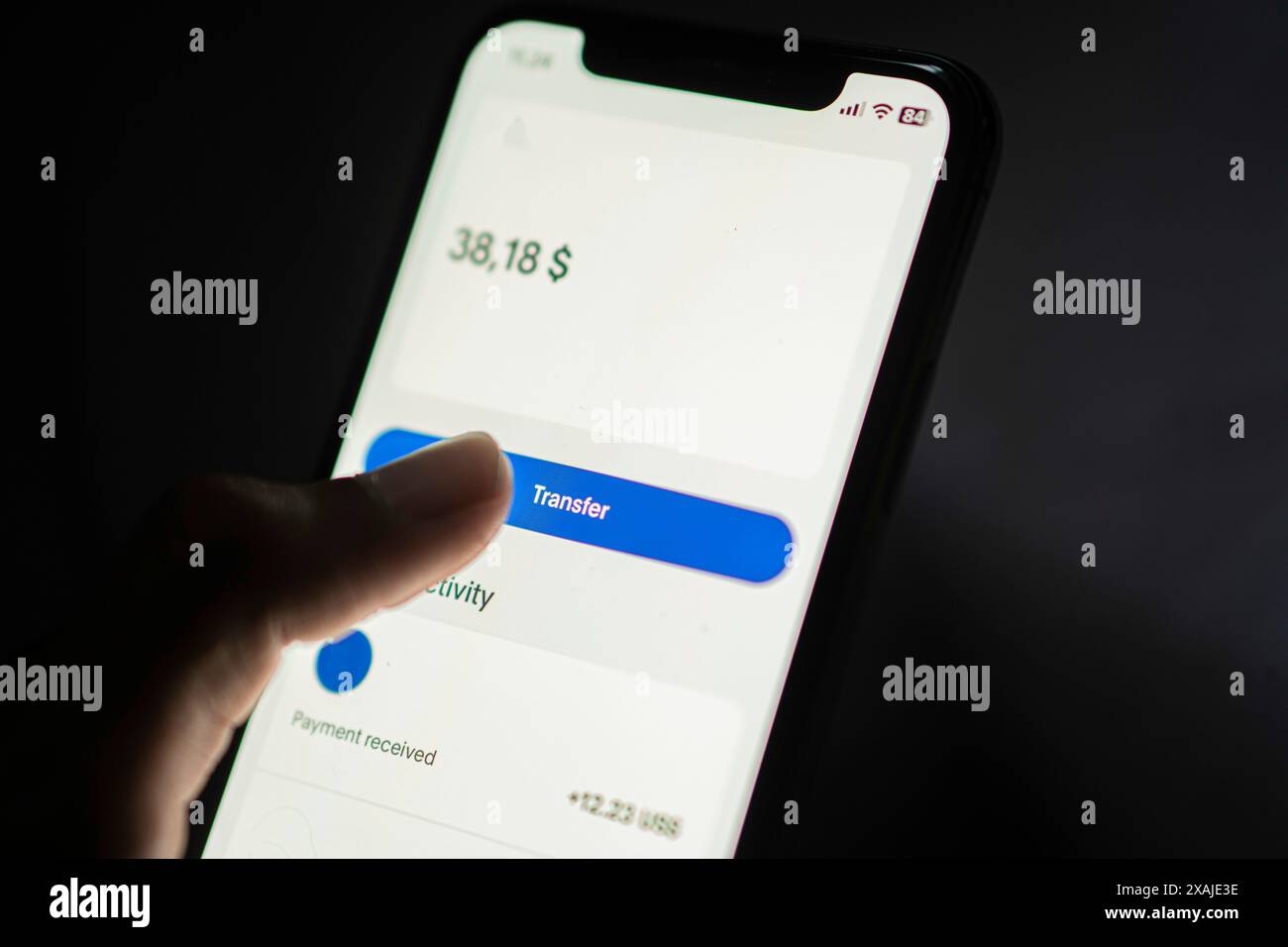 Close-up of a smart phone screen showing a digital wallet app with a balance of 38.18 dollars. A finger is about to tap the transfer button. Stock Photo