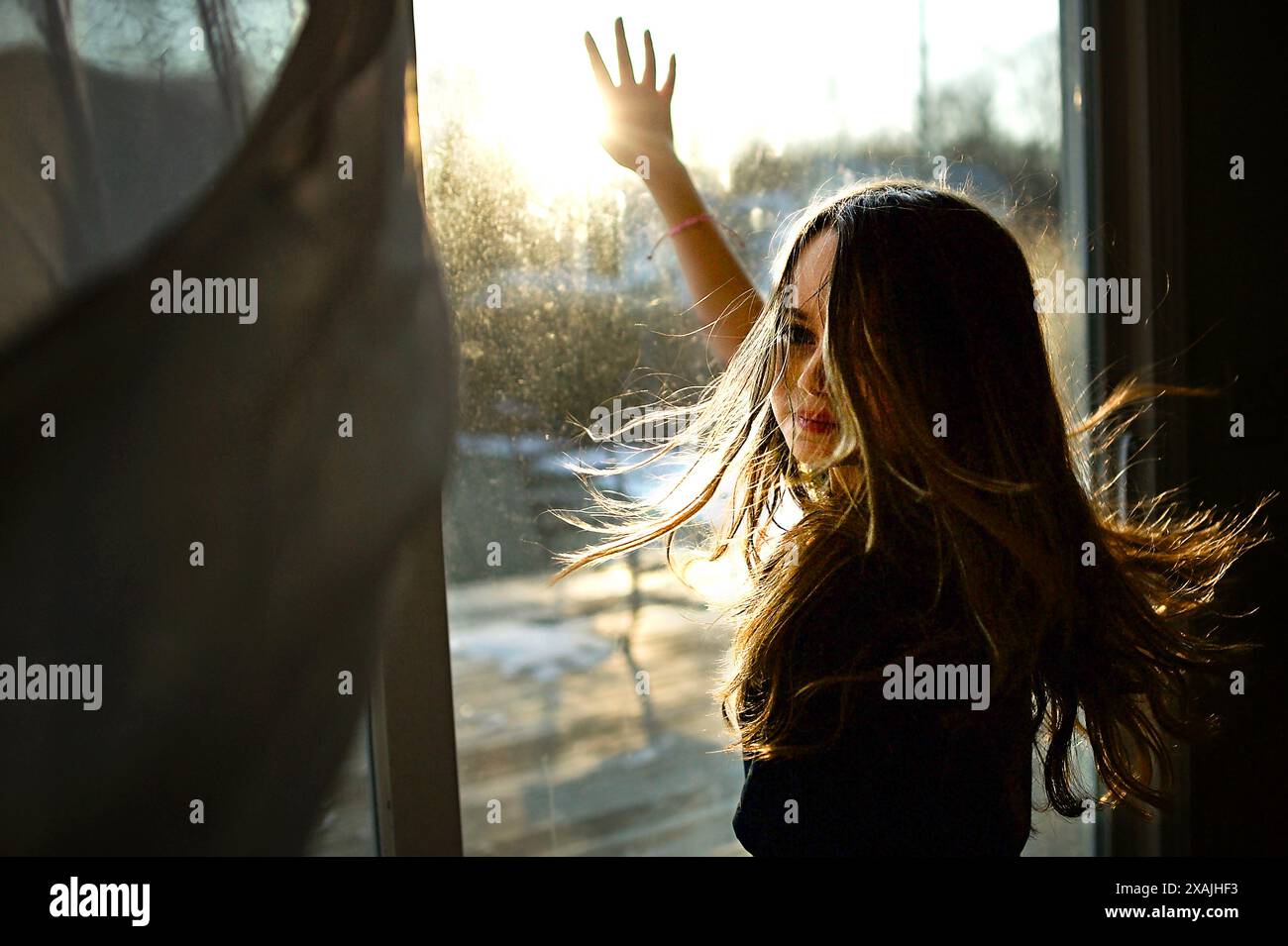 Young girl long blonde hair looking at camera reaching for sun Stock Photo