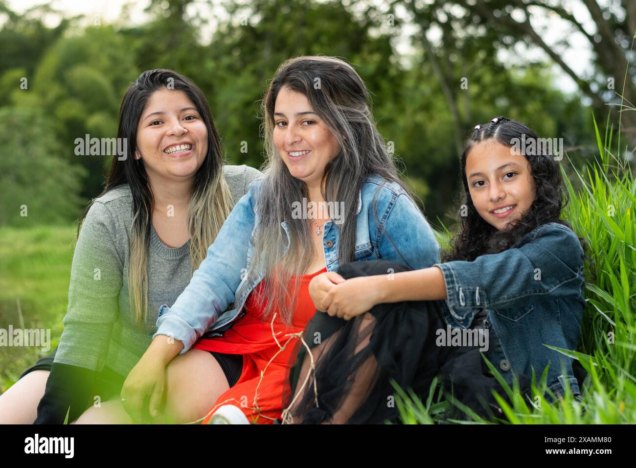 three latina girls, friends together laughing loudly sitting on the ...