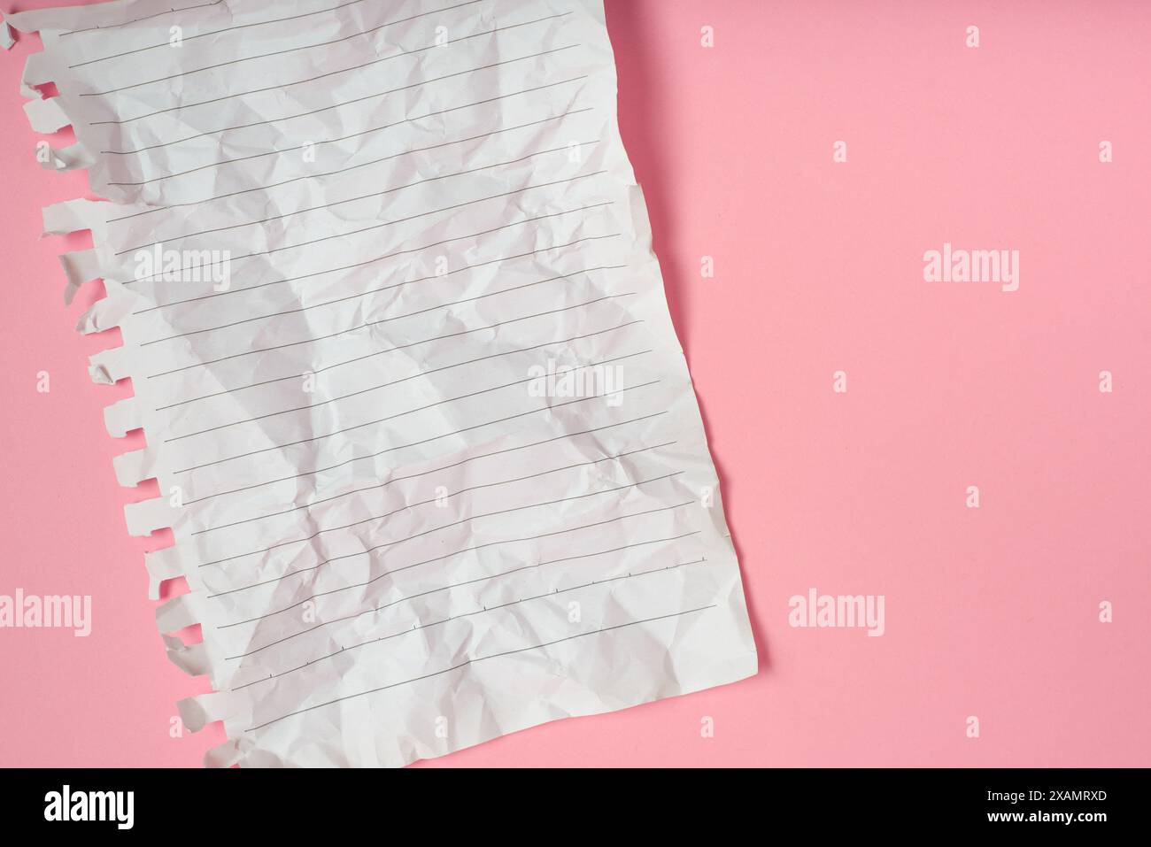 Wrinkled notebook sheet with stripes on pink background. Stock Photo