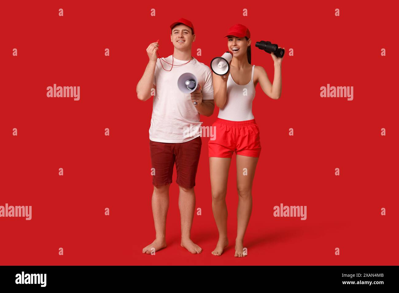 Lifeguards with megaphones and binoculars on red background Stock Photo