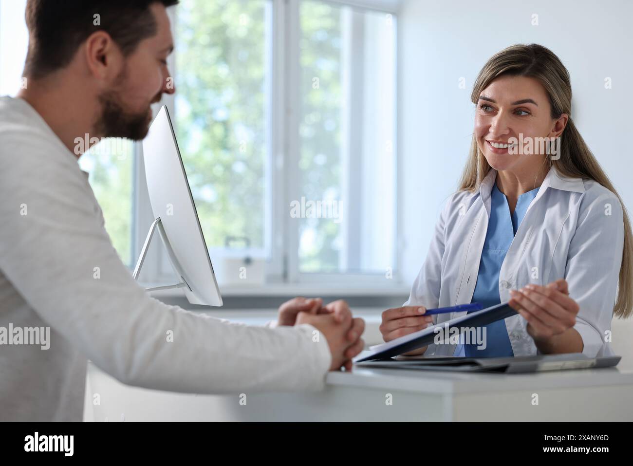Professional doctor working with patient at white table in hospital ...