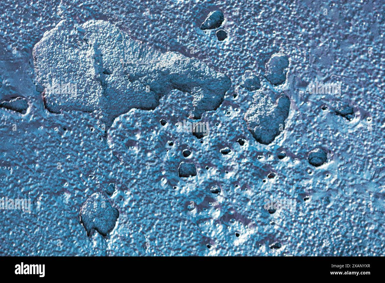 Blue surface with small holes cracks, providing a textured and visually appealing pattern Stock Photo