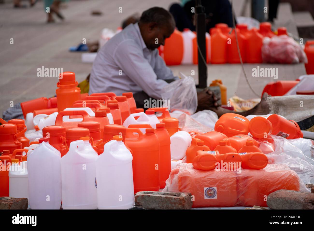 Shopkeeper selling saffron white water bottles used to fill holy water from river ganga for prayers and rituals Stock Photo Alamy