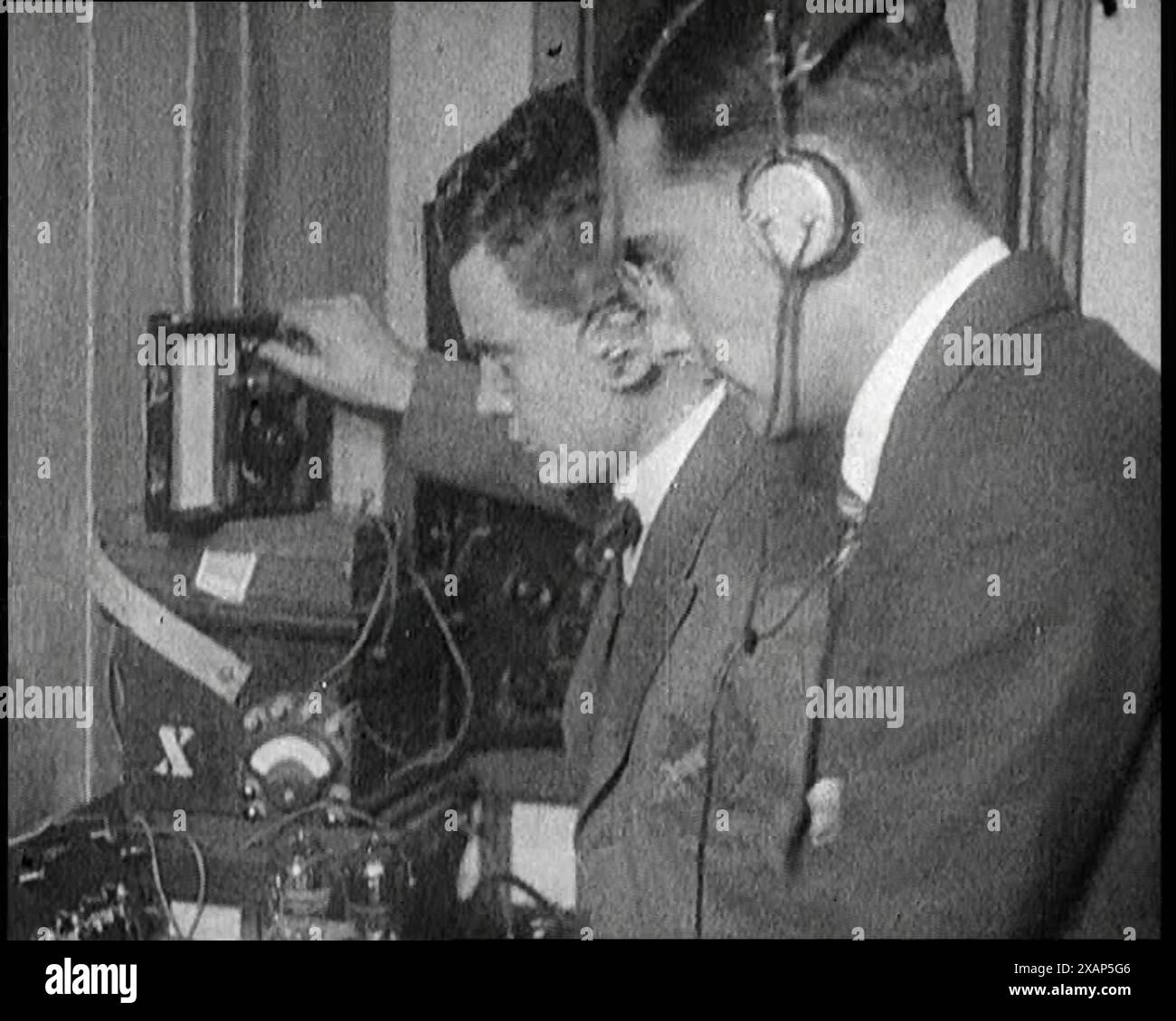 Two Men Wearing Headphones and Calibrating Wireless Equipment, 1922. From &quot;Time to Remember - Sitting Still And Going Slowly&quot;, 1922 (Reel 4); a review of events in 1922 including Irish Troubles, war between Greece and Turkey and developments in aviation and radio. Stock Photo