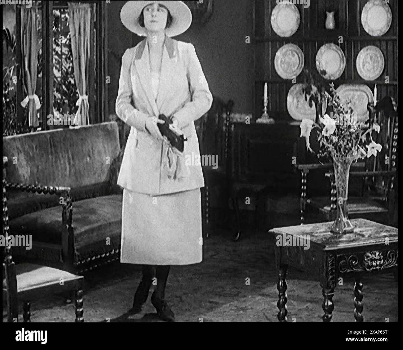 A Female Civilian Modelling a Two Piece Suit and Hat Posing in a Drawing Room, 1920s. From &quot;Time to Remember - Teenage Flapper&quot;, 1920s (Reel 1); a dcumentary about women's lives in the 1920s - great commentary by Joyce Grenfell. Stock Photo