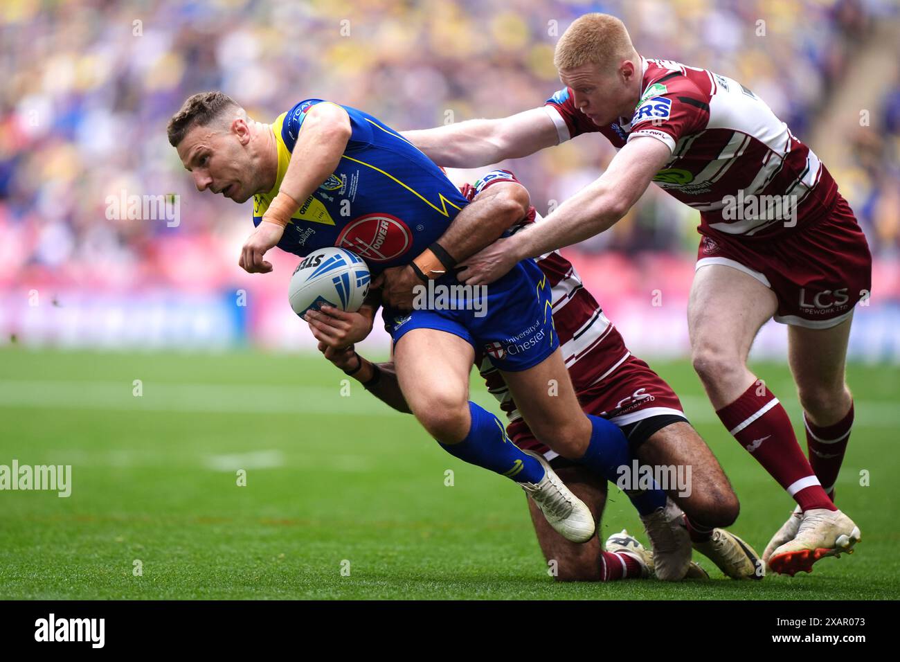 Warrington Wolves' George Williams is tackled by Wigan Warriors' Zach Eckersley (right) and team-mate during the Betfred Challenge Cup final at Wembley Stadium, London. Picture date: Saturday June 8, 2024. Stock Photo