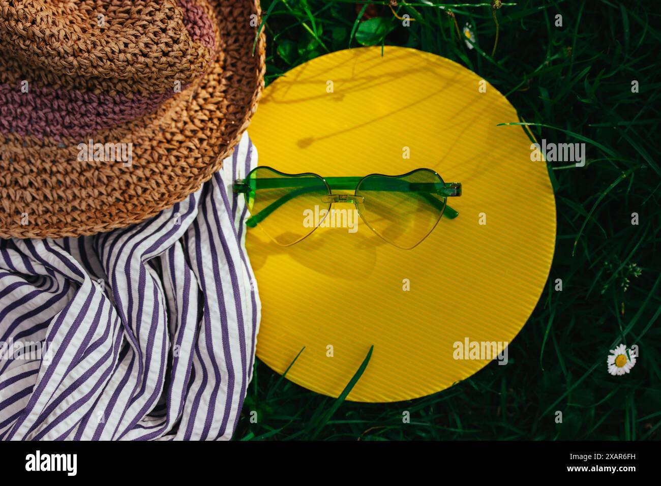 Female boho style straw hat and green heart-shaped sunglasses lie on a ...