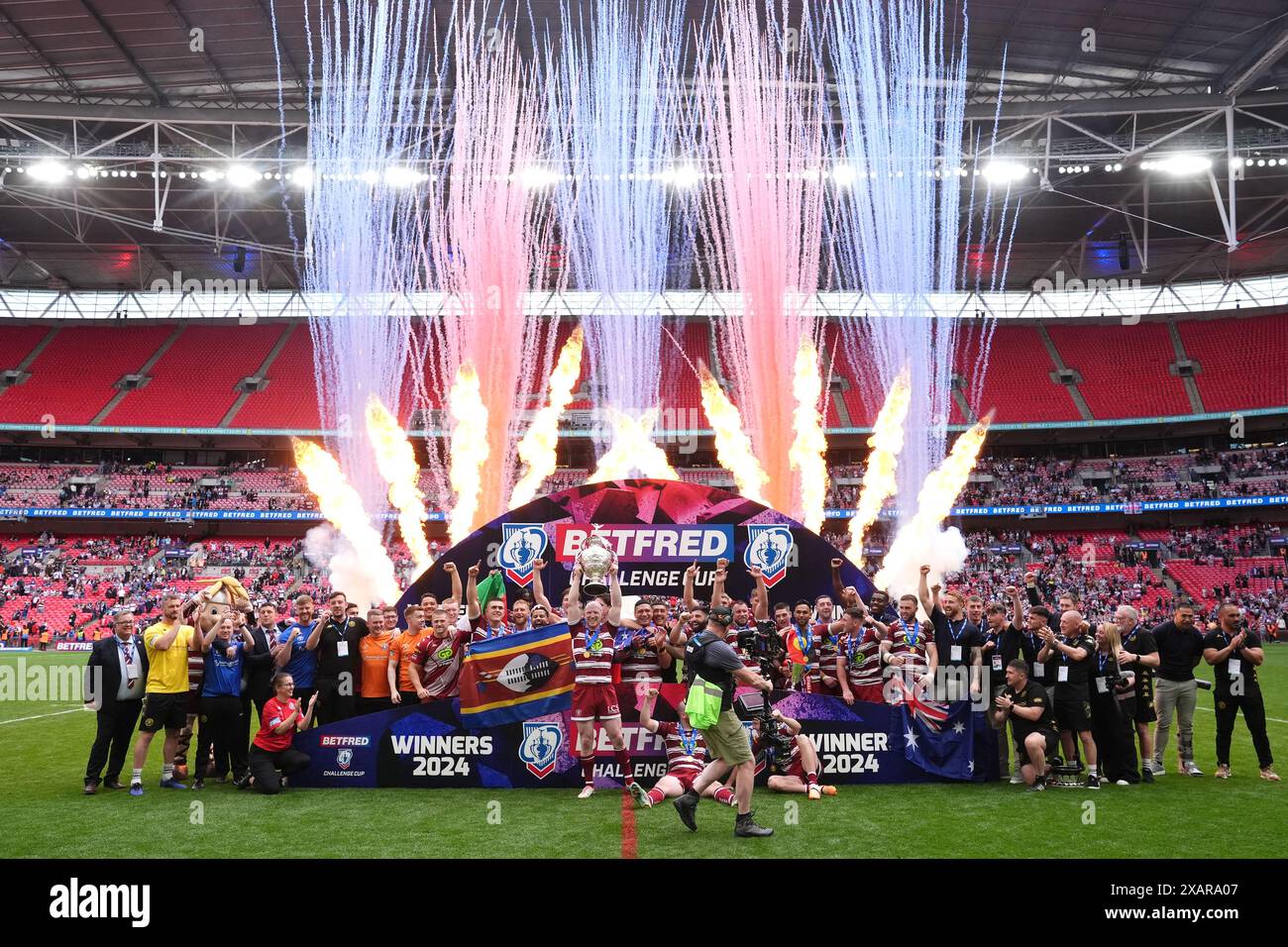 Wigan Warriors' Liam Farrell (centre) lifts the trophy with team-mates as pyrotechnics are set off after victory in the Betfred Challenge Cup final at Wembley Stadium, London. Picture date: Saturday June 8, 2024. Stock Photo