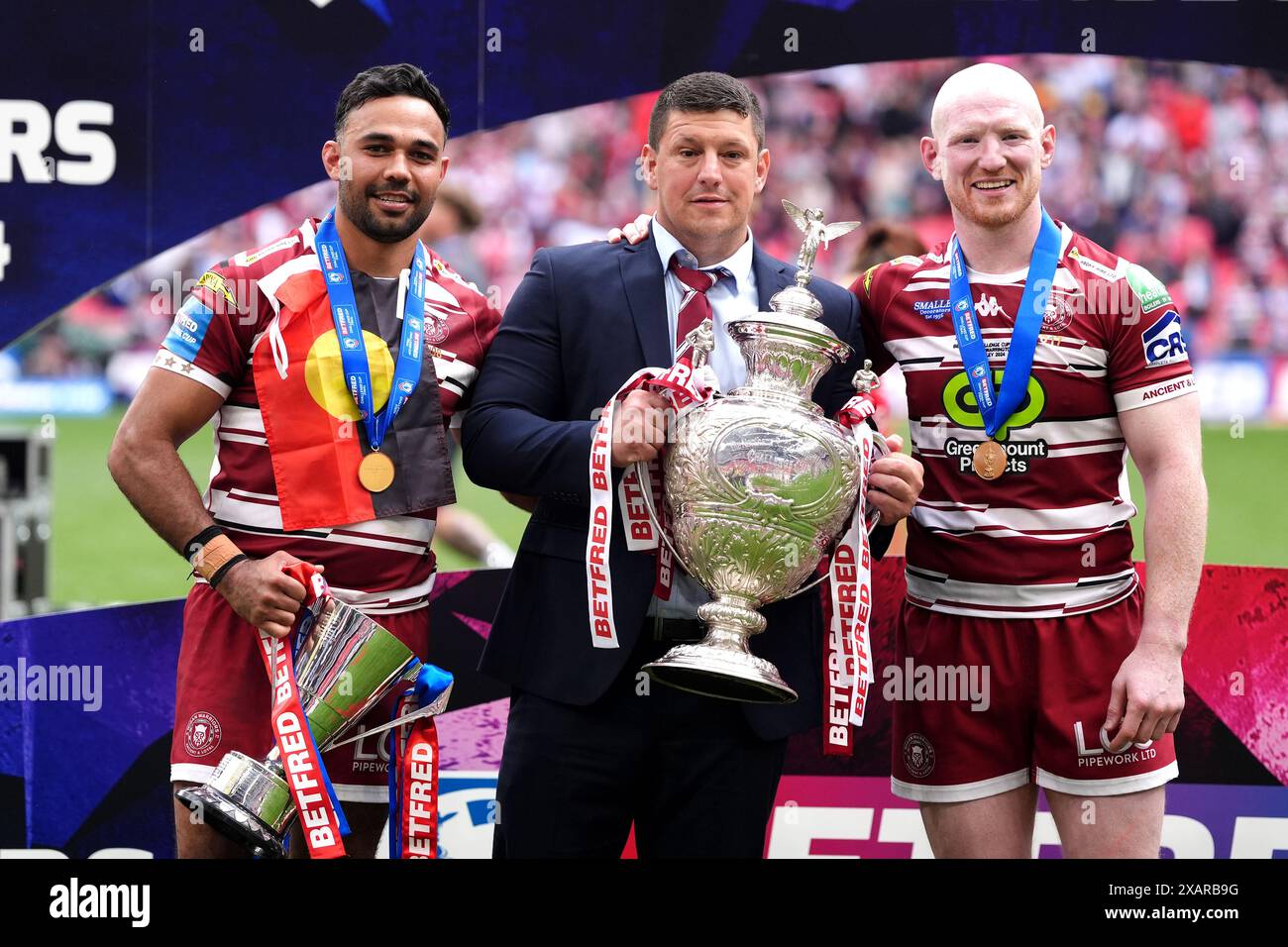 Wigan Warriors head coach Matt Peet (centre) pose with the trophy, player Bevan French (left) with the man of the match trophy, and Liam Farrell celebrate after the final whistle in the Betfred Challenge Cup final at Wembley Stadium, London. Picture date: Saturday June 8, 2024. Stock Photo