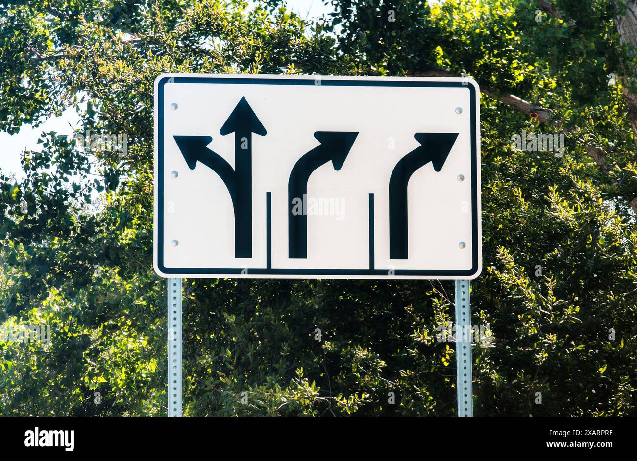 A white traffic sign with black arrows informing motorists of left turn ...