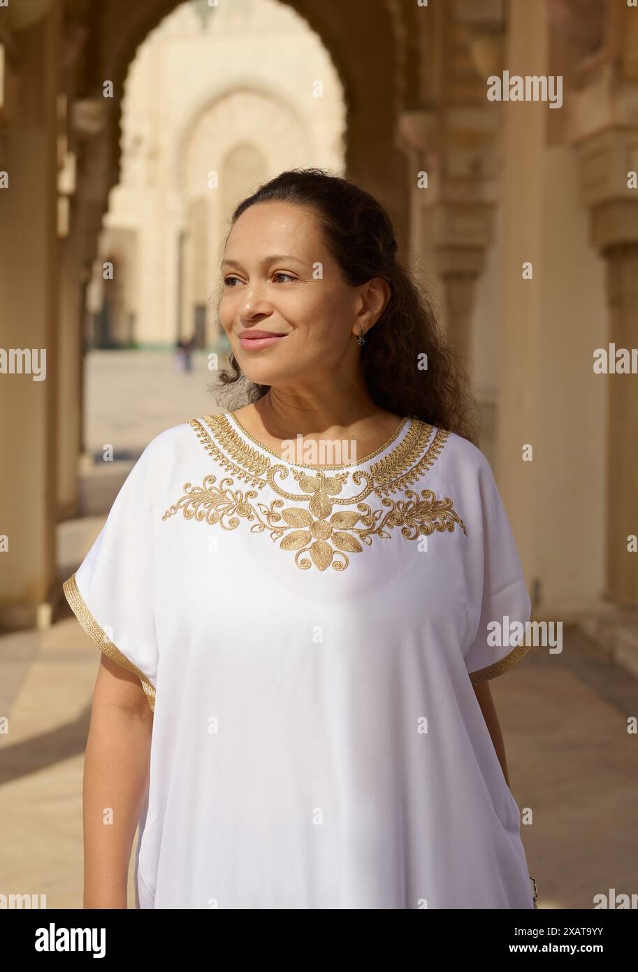 A woman dressed in a white and gold traditional outfit stands under an ...