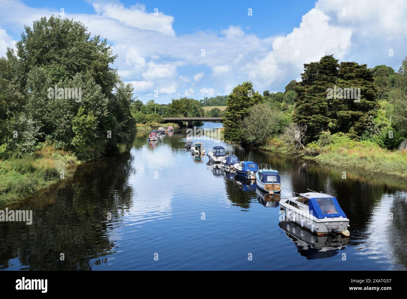 A line of boats moored on the River Dart on a sunny day in summer, Totnes, South Hams, South Devon, England, UK.  rivers waterway riverbank waterways Stock Photo