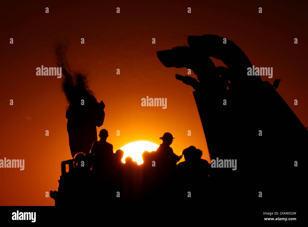 Passengers on a ferry pass by the Statue of Liberty as the sun sets in