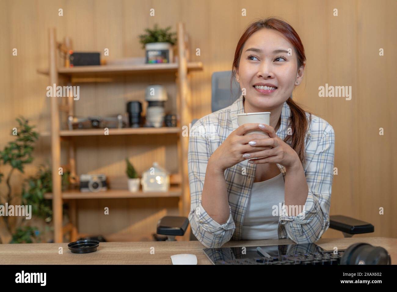 A young woman drinks coffee while working at home Stock Photo