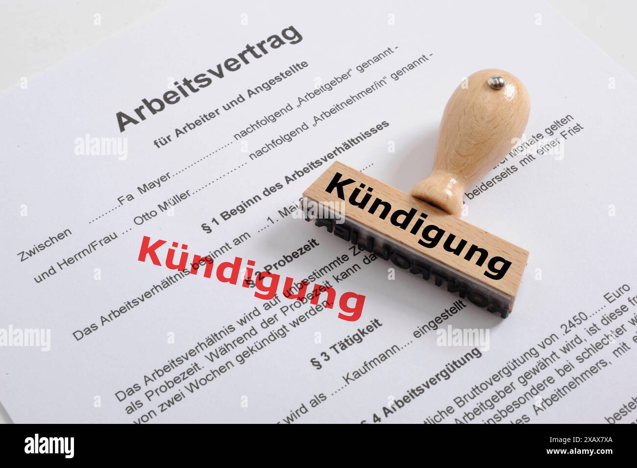 Kündigung von Arbeitsvertrag und Arbeitsplatz Ein Holzstempel liegt auf einem Arbeitsvertrag mit der Aufschrift Kündigung *** Termination of employmen Stock Photo