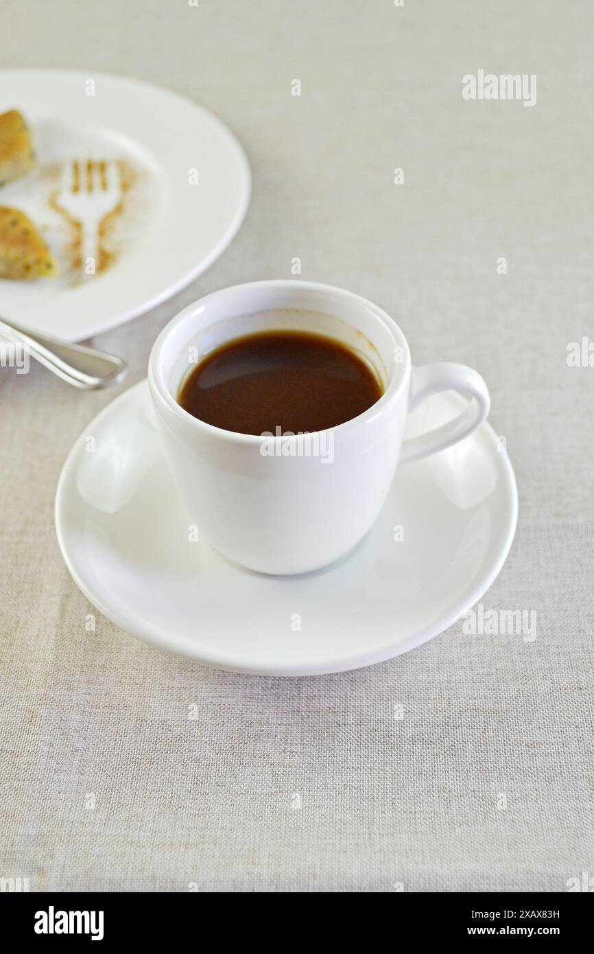 Espresso coffee white cup on a table in front of a plate of sweet. Minimalist decoration with copy space Stock Photo