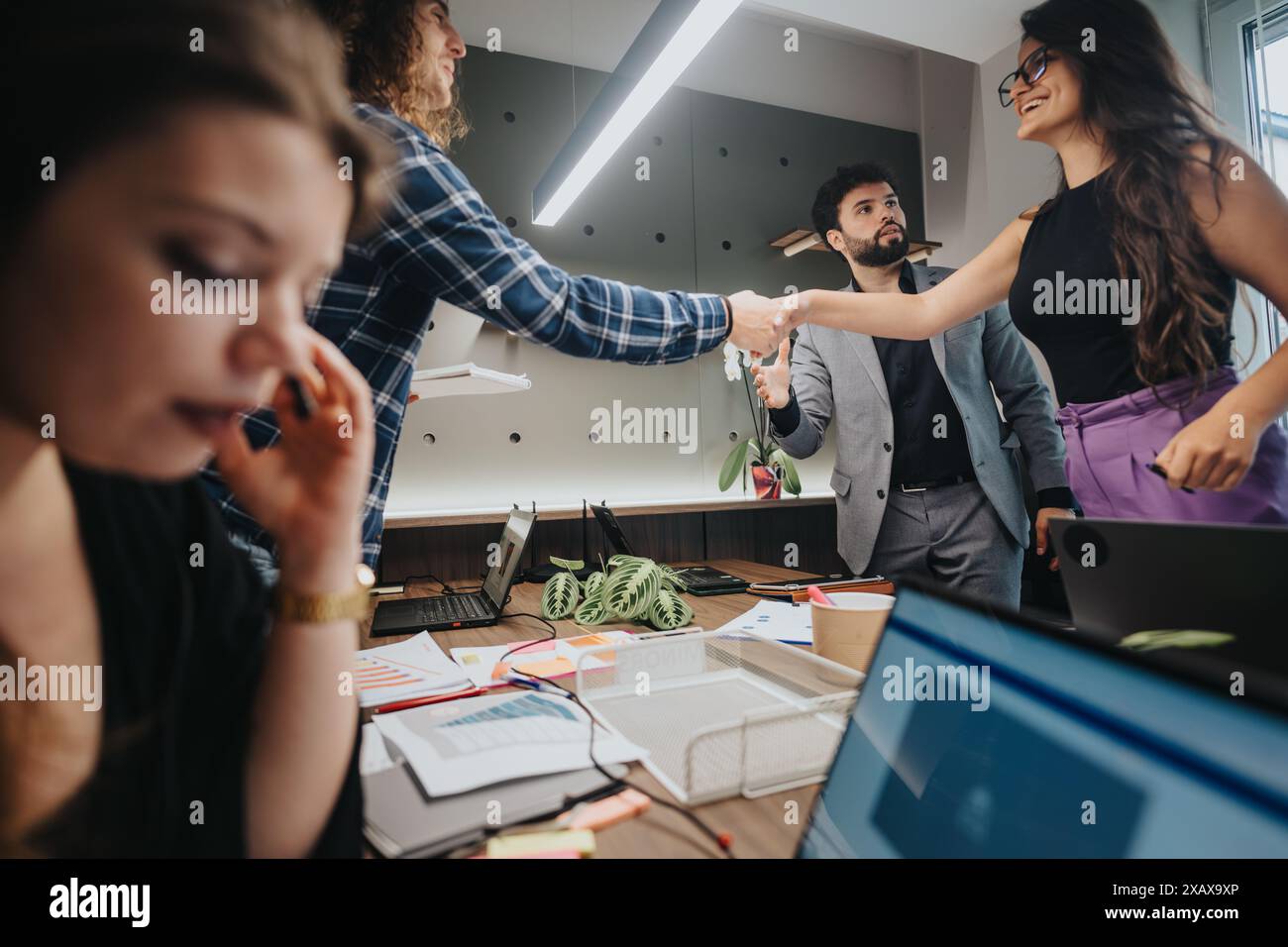 Business team in meeting at modern office with two colleagues shaking hands Stock Photo