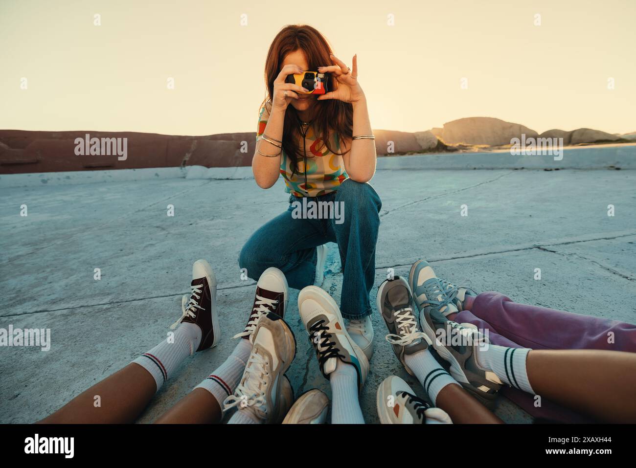 Group of friends enjoying outdoor photography session. Woman using camera to capture moments with friends. Casual and fun atmosphere. Stock Photo