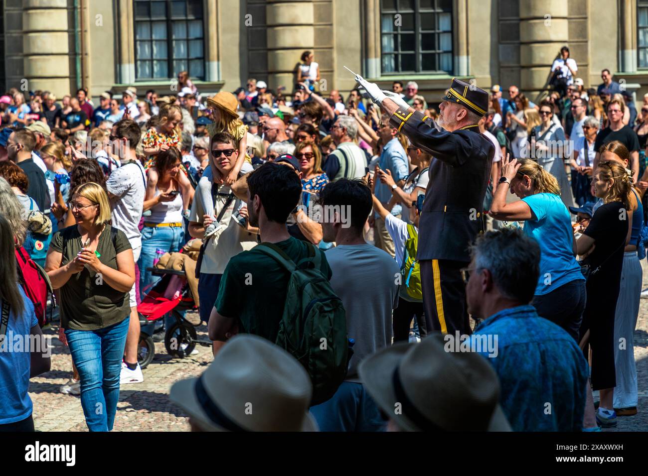 The conductor of the cavalry band stands on a platform in the middle of the tourists and conducts the concert of marching music and Abba songs. Royal Guards Ceremony at the Royal Palace of Stockholm. Changing of the guard in front of the Swedish Royal Palace in Stockholm with musical accompaniment from the mounted band. Yttre borggården, Stockholm, Sweden Stock Photo