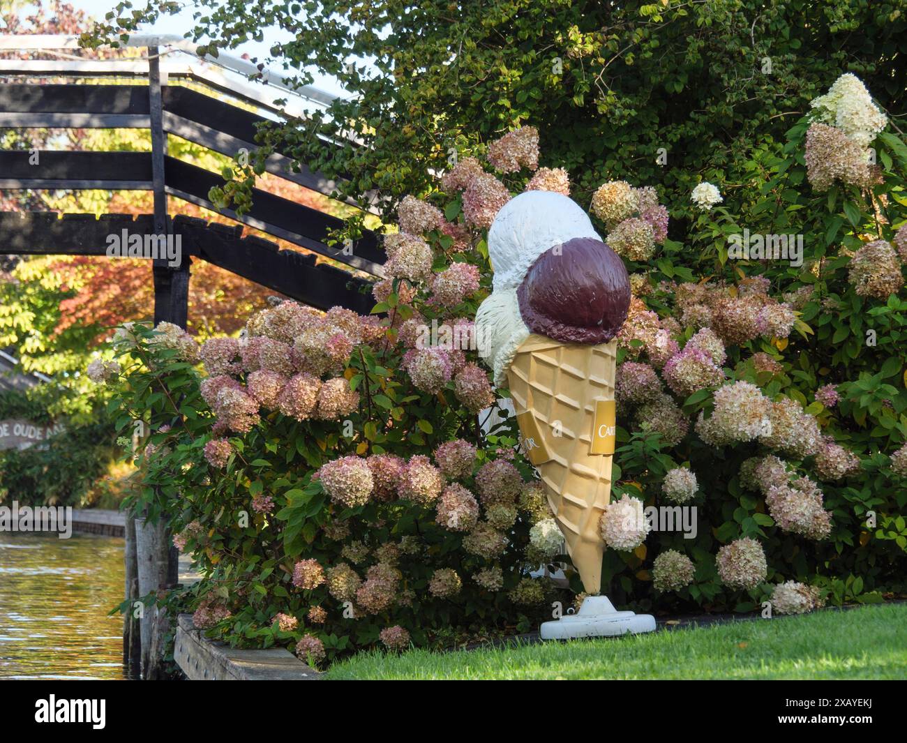 Large ice-cream cone decoration between hydrangea flowers on a canal next to a wooden bridge, giethoorn, Netherlands Stock Photo