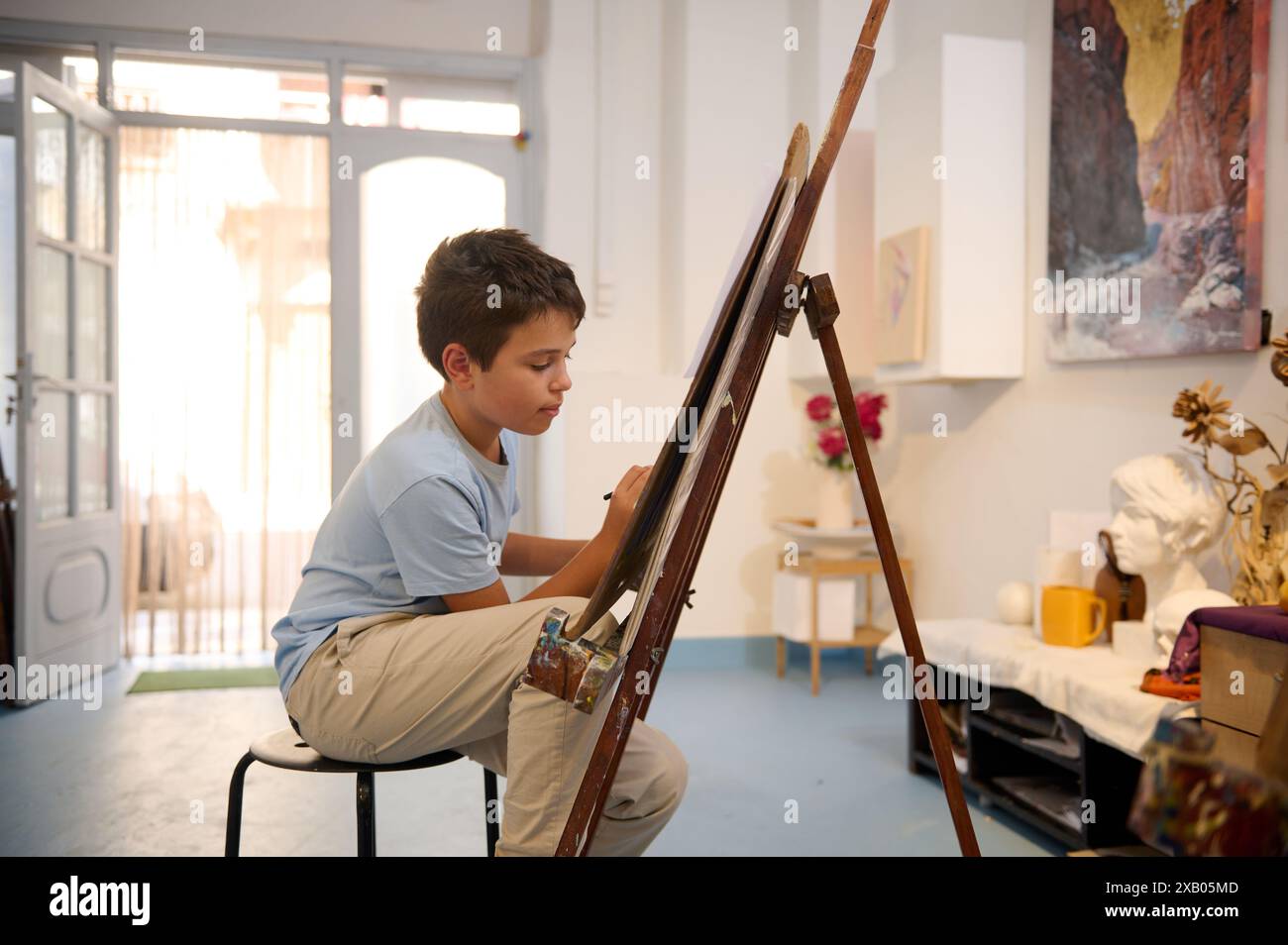 Kids have art class, drawing, painting with teacher in workshop. A boy ...