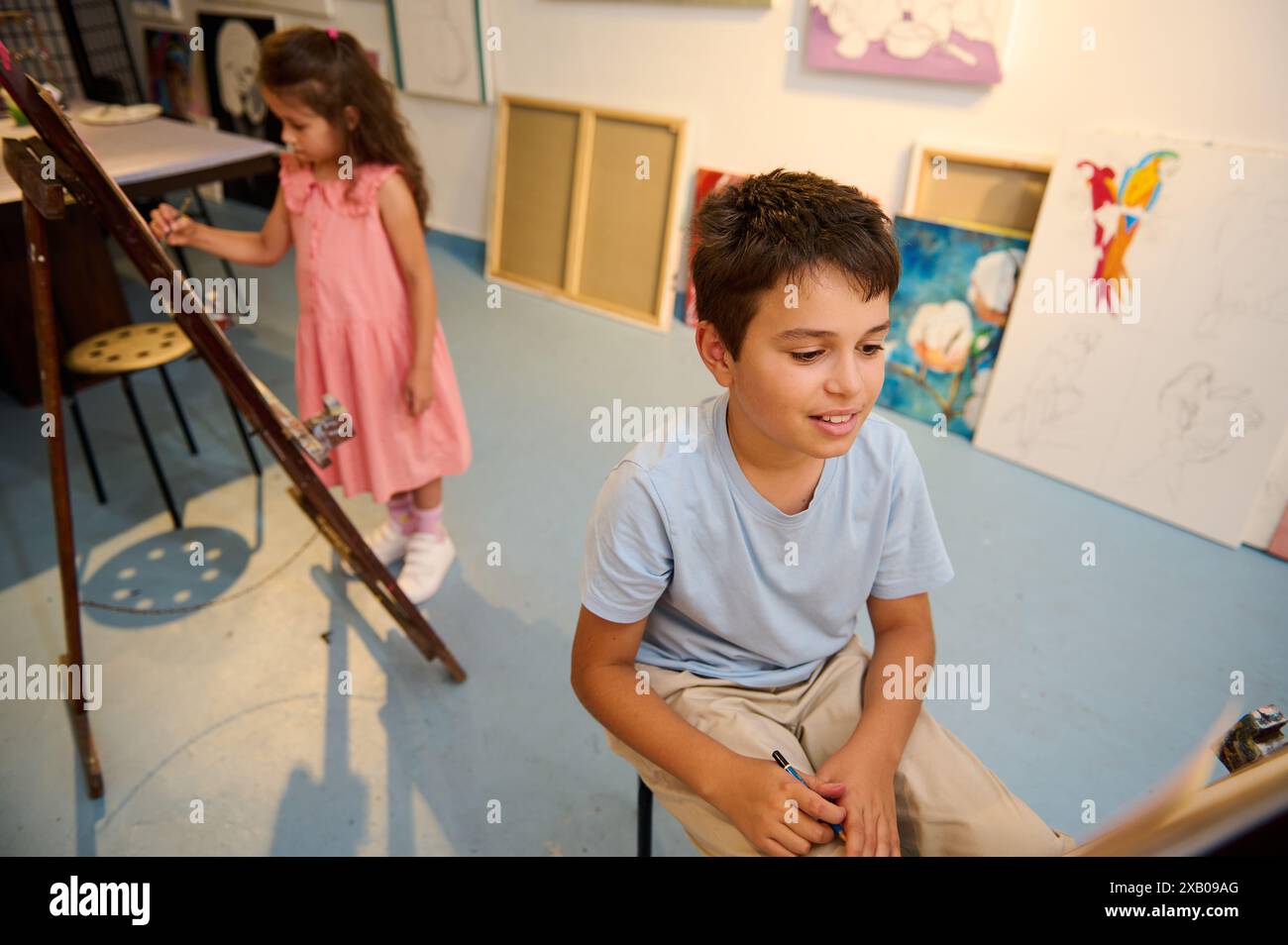 Kids enjoying art class drawing and painting with teacher in workshop ...
