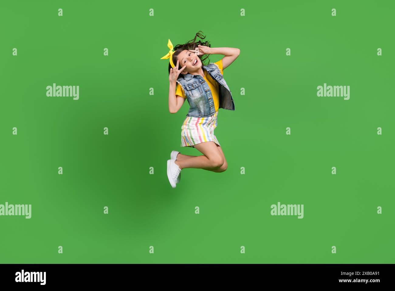 Photo of positive girl kid jump make v sign face isolated green color ...