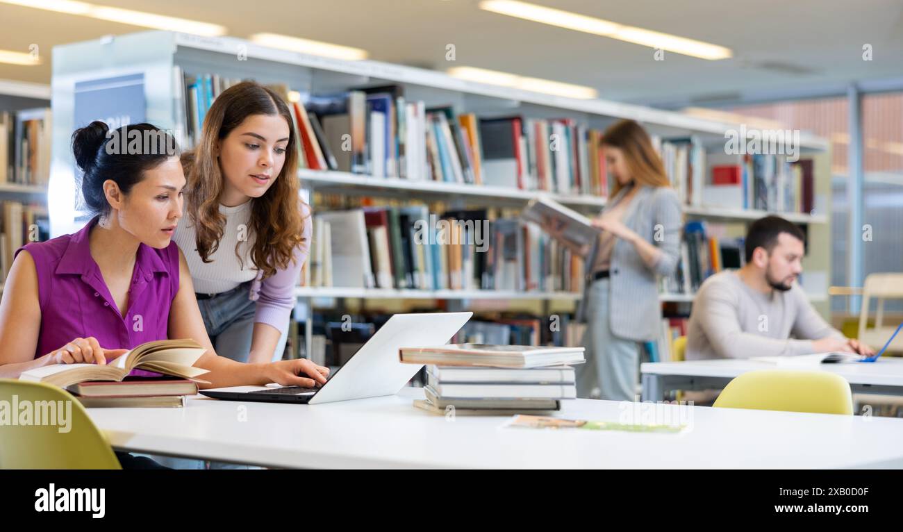 Two female colleagues working on joint project in library Stock Photo