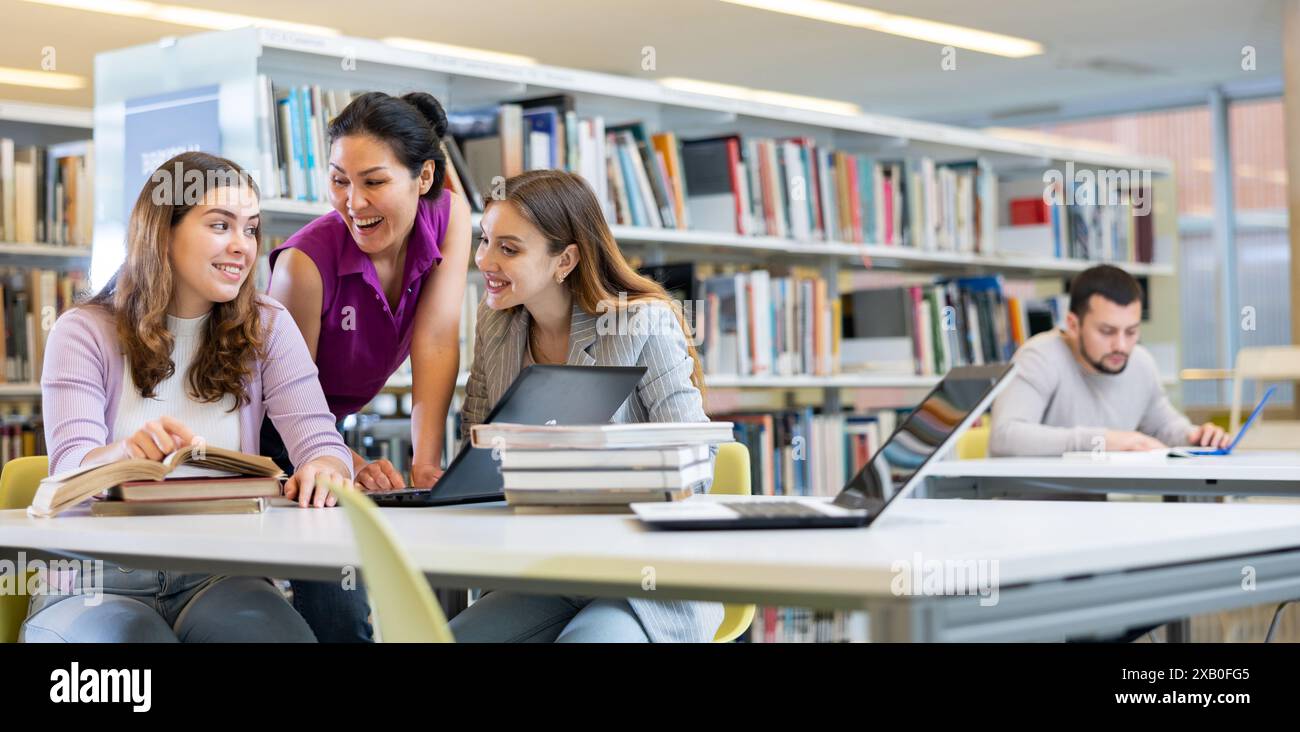 Three female friends studying together at library Stock Photo