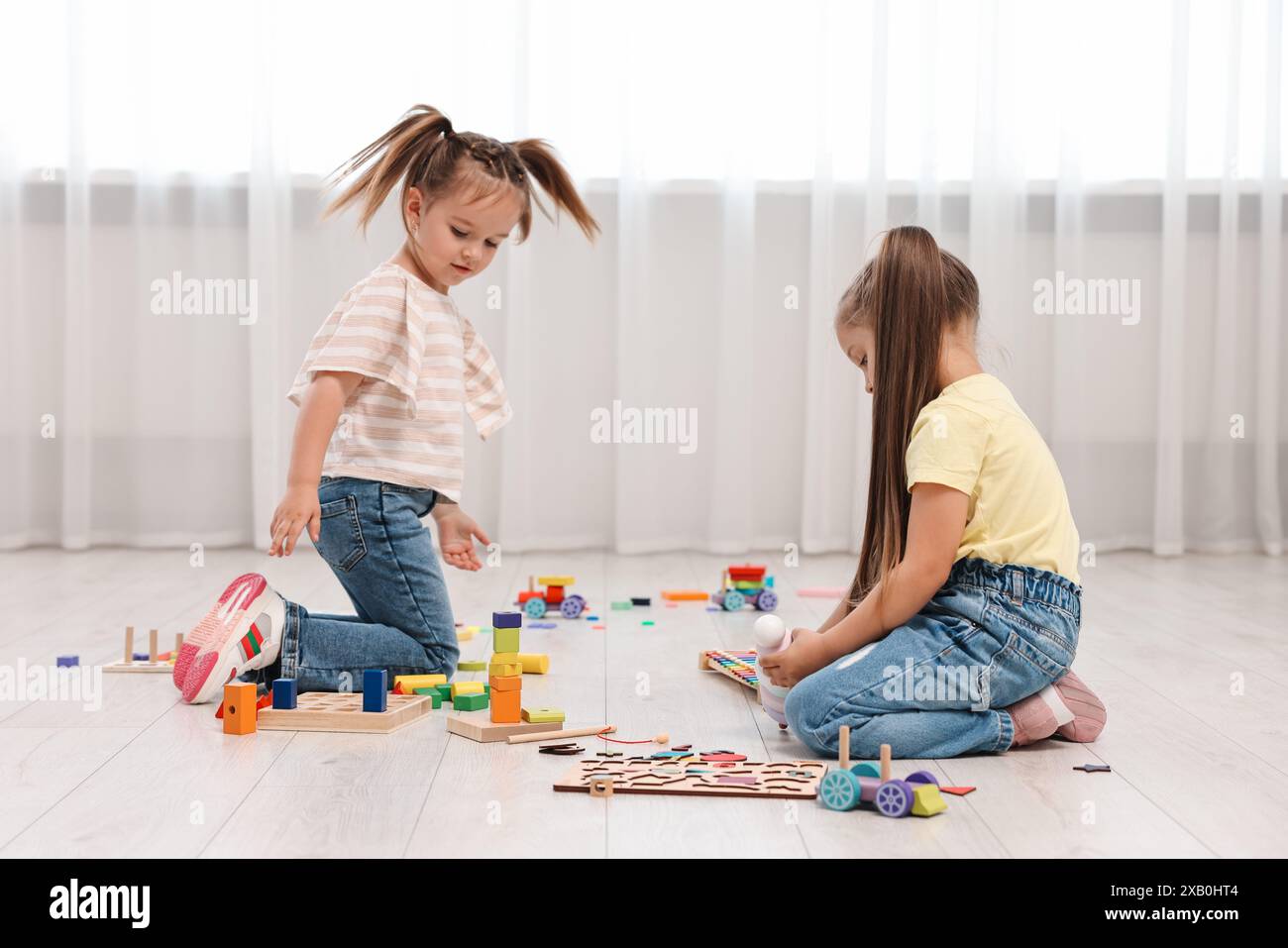 Cute little children playing together on floor indoors Stock Photo - Alamy