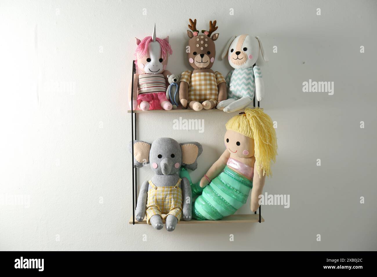 Shelf with cute toys on light wall. Baby room interior element Stock Photo