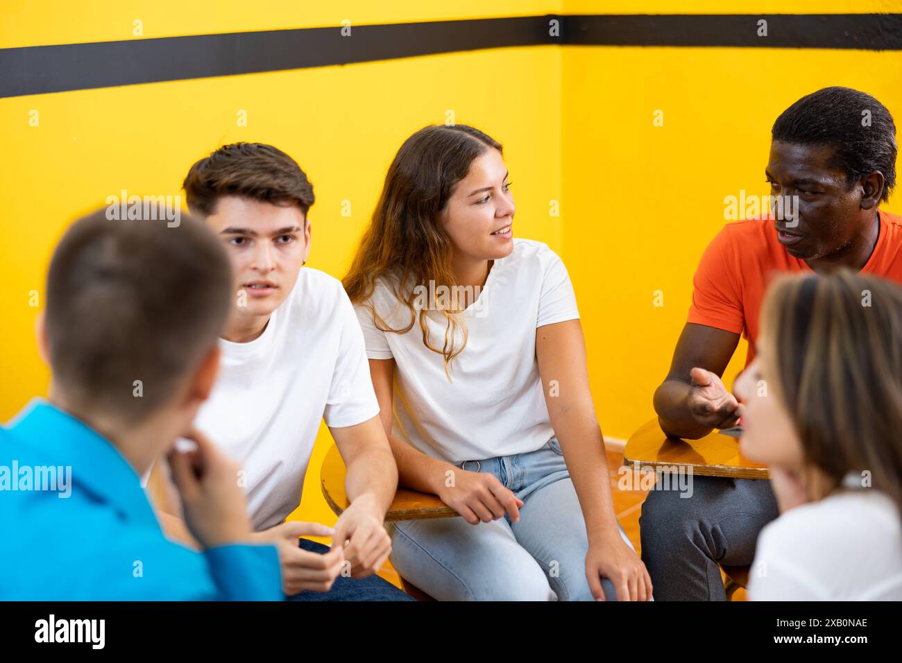 Friendly adult students chatting cheerfully while sitting in classroom Stock Photo