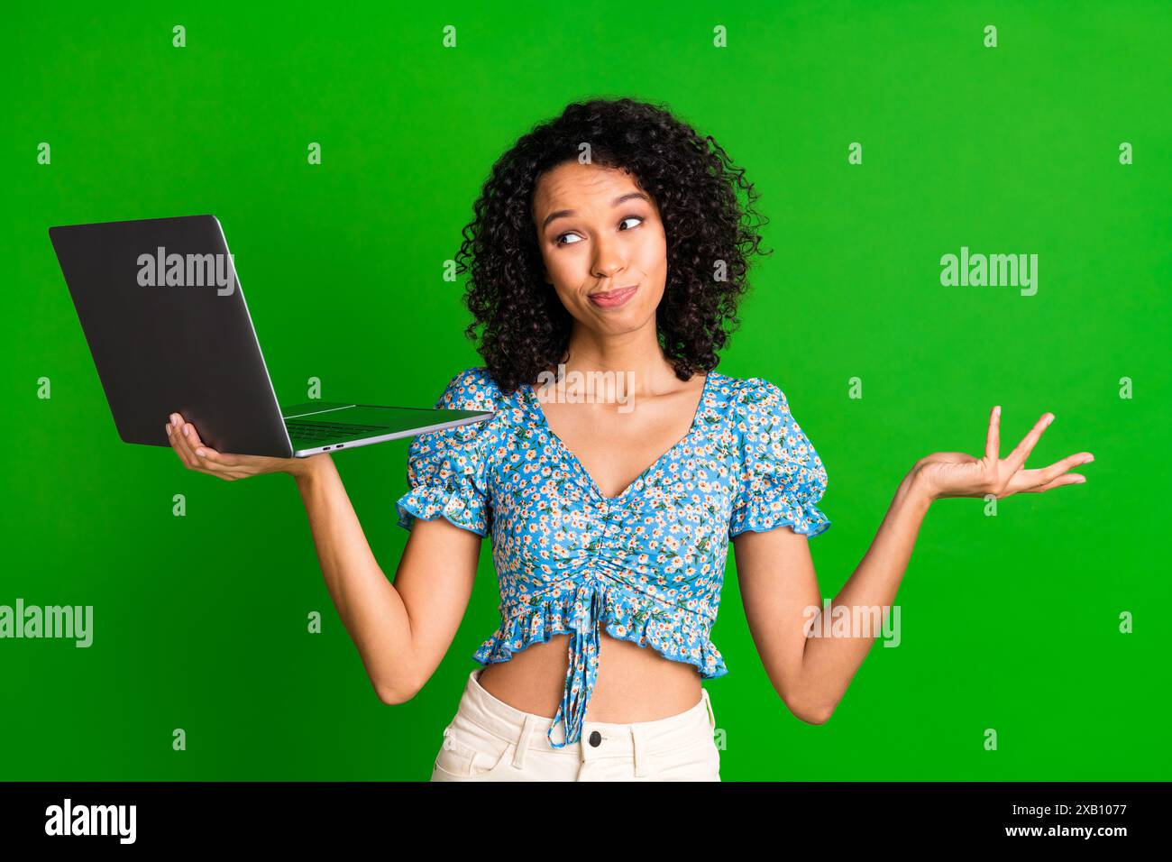 Photo of nice young woman shrug shoulder use laptop wear top isolated on green color background Stock Photo Alamy