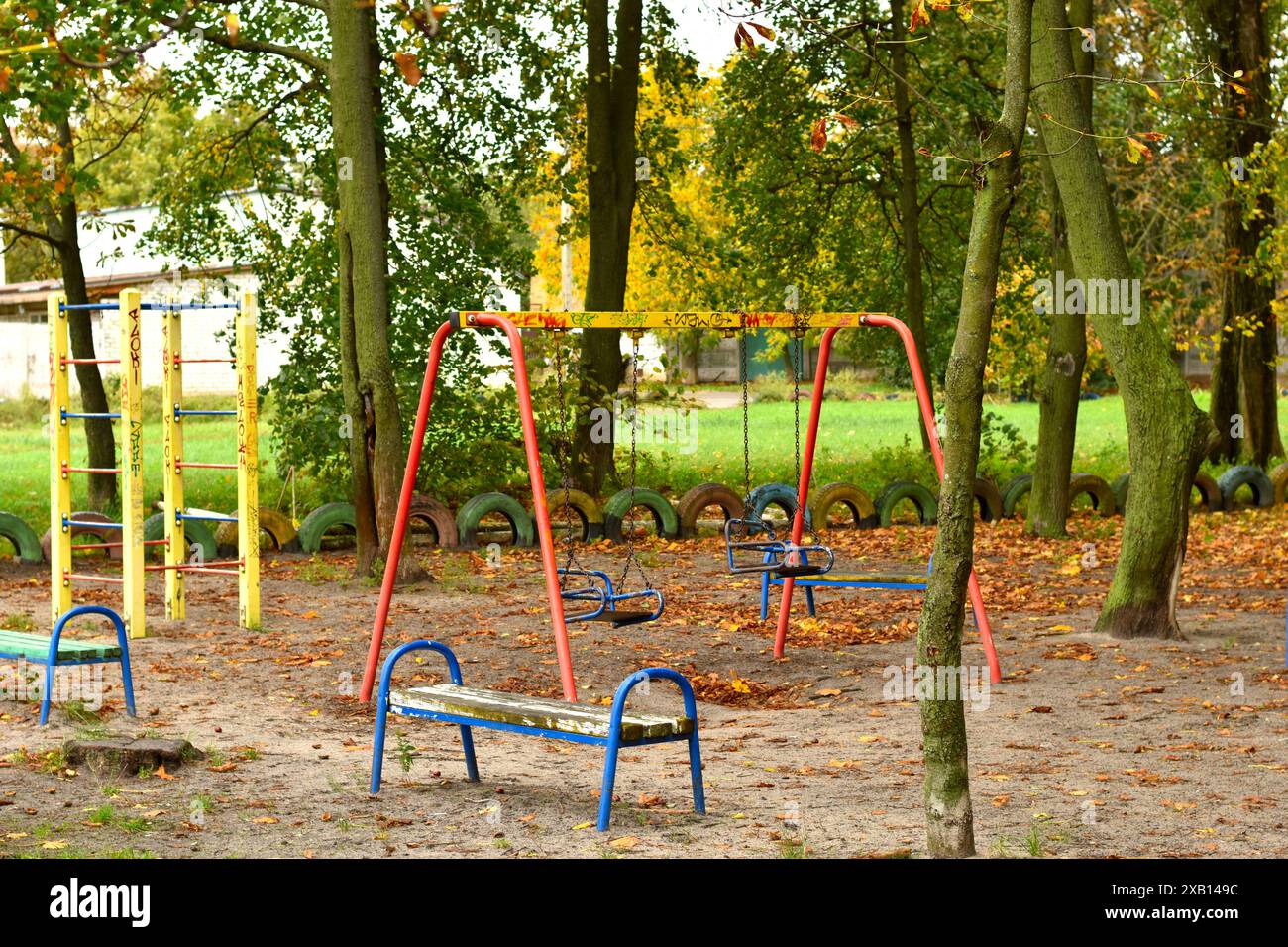 Playground Tree Fall A park of tall trees in autumn, yellow leaves on the lawn and a ...