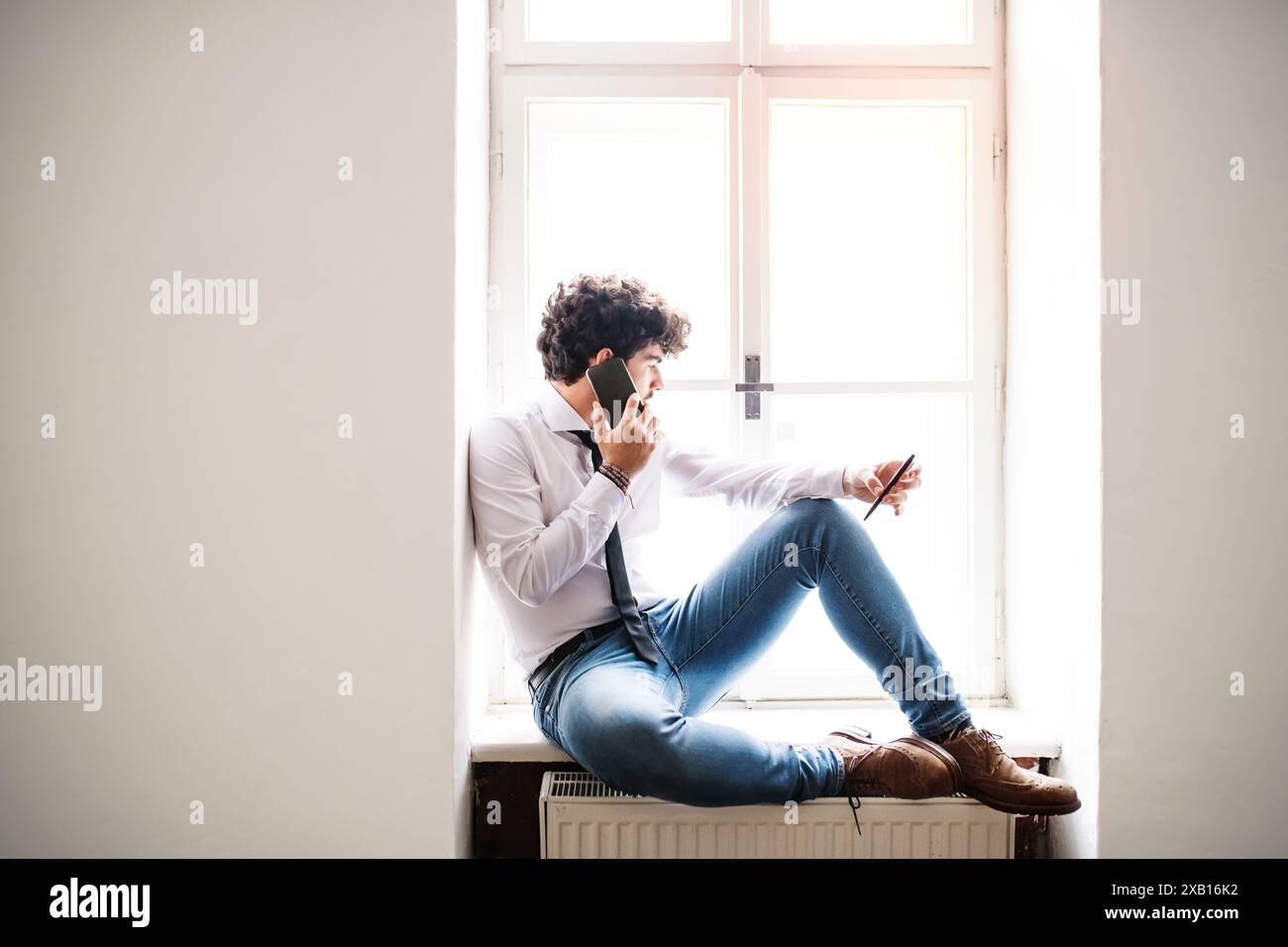 Young businessman working on new project in a startup company office, making phone call. Working in co-working space. Stock Photo