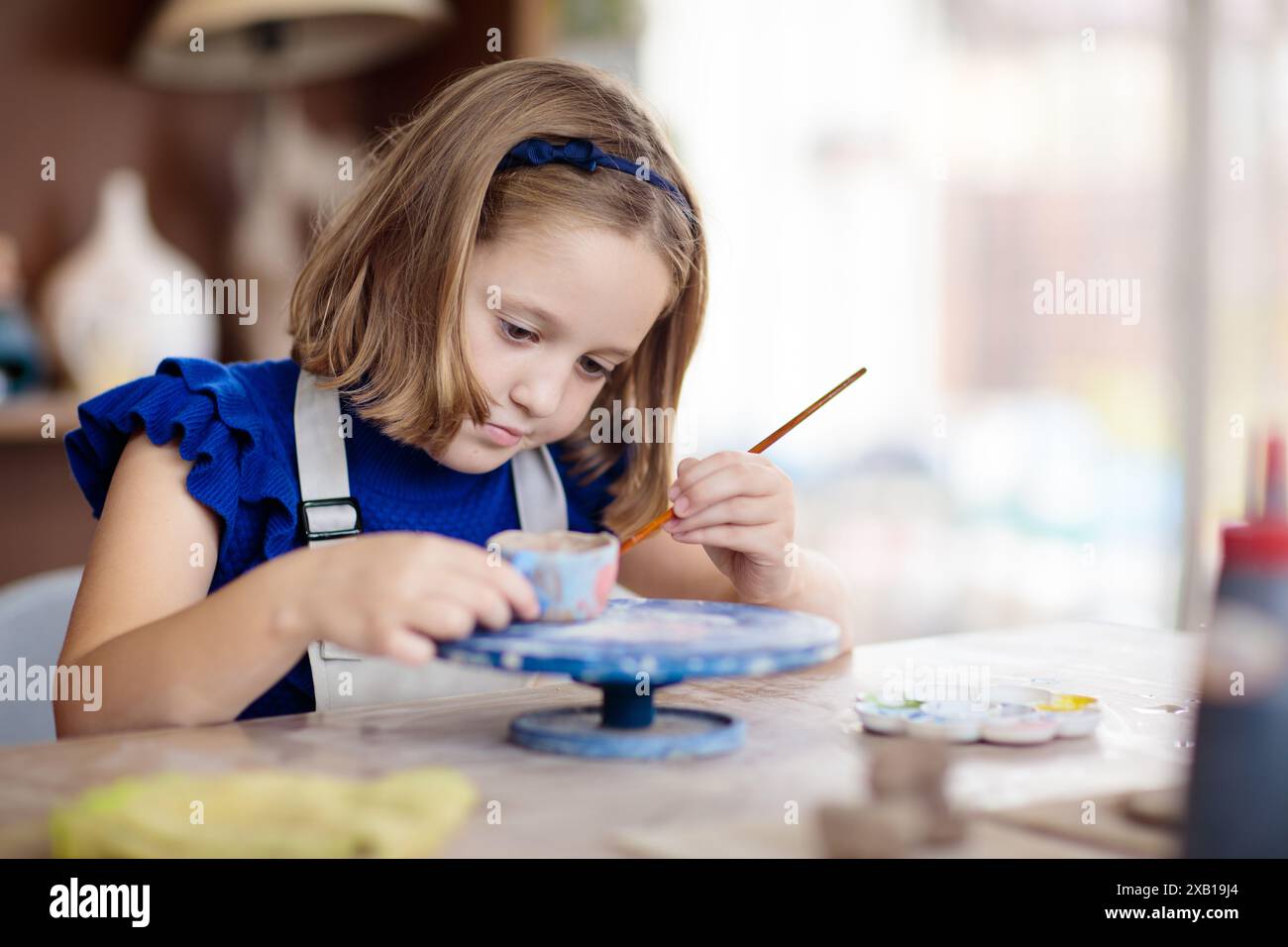 Child Creating Something Child working on pottery wheel. Kids arts and crafts class in workshop ...