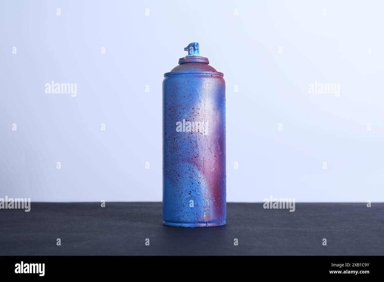 Spray paint can on black surface against white background Stock Photo