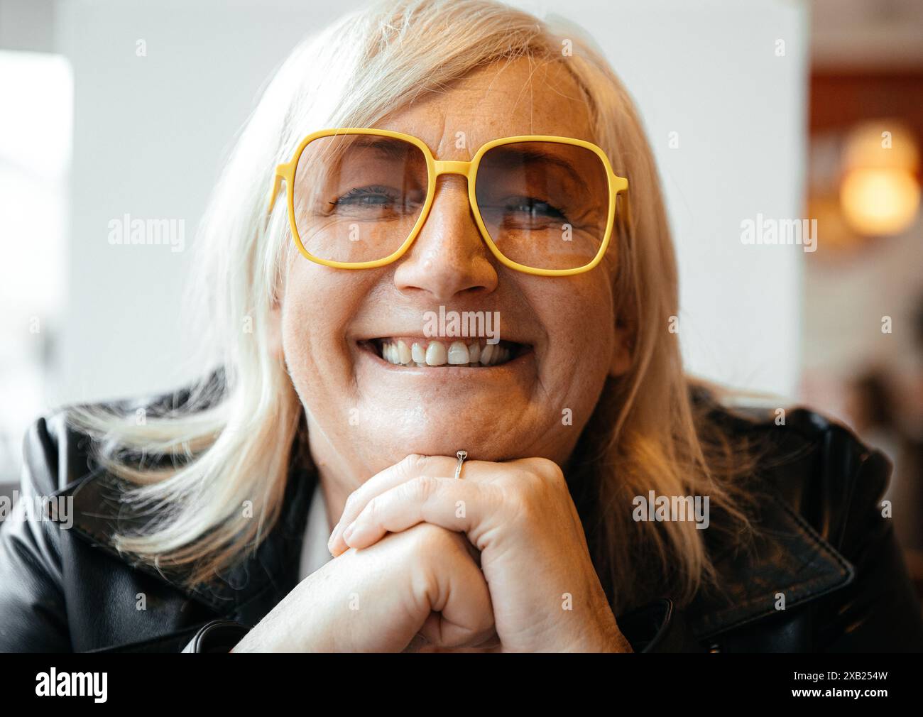 Smiling older woman with yellow glasses and blonde hair Stock Photo