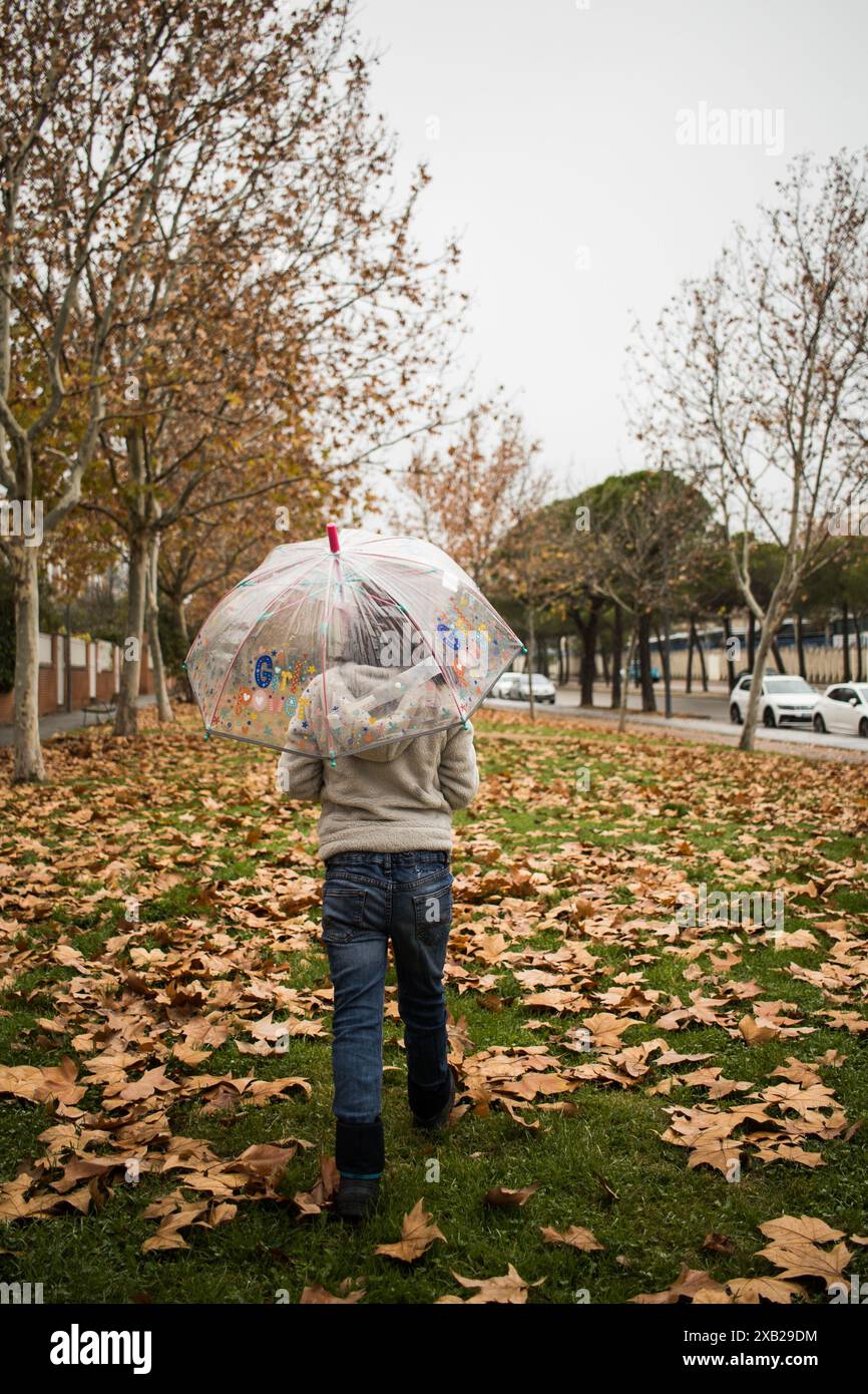 girl with umbrella walking at the rain in city autumn park, back view ...