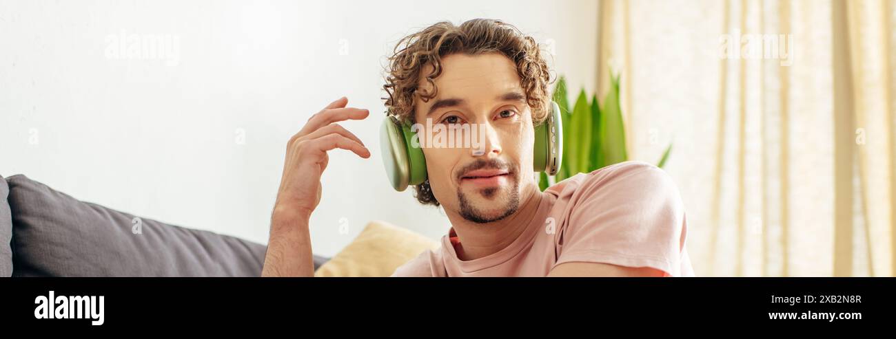 Handsome man sitting on a couch with headphones. Stock Photo