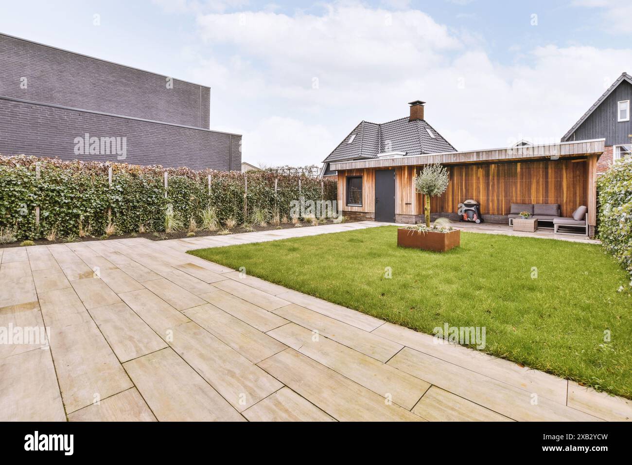 Neat paved patio with sitting area and small garden near wooden fence ...