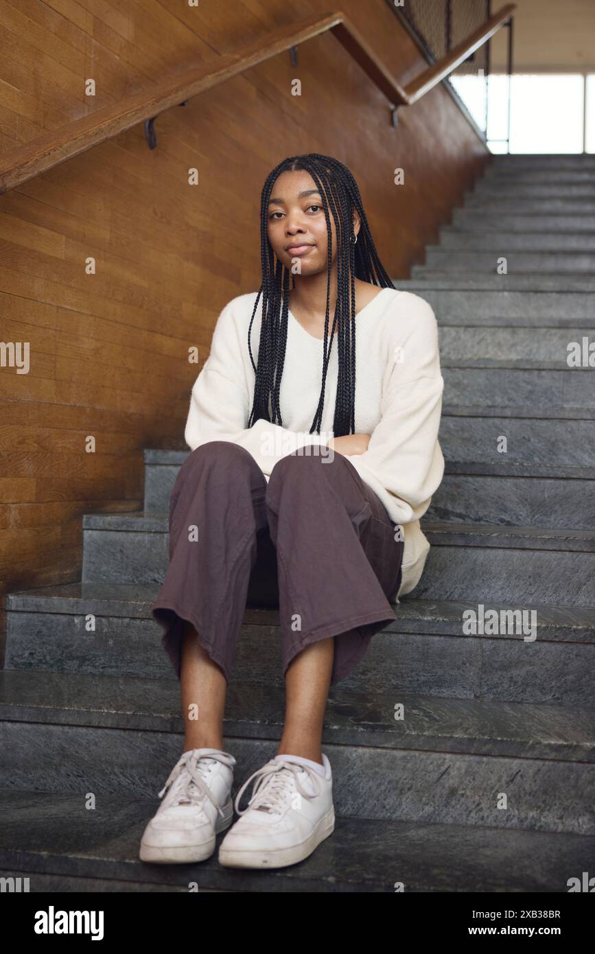 Young woman with braided hair sitting on staircase Stock Photo