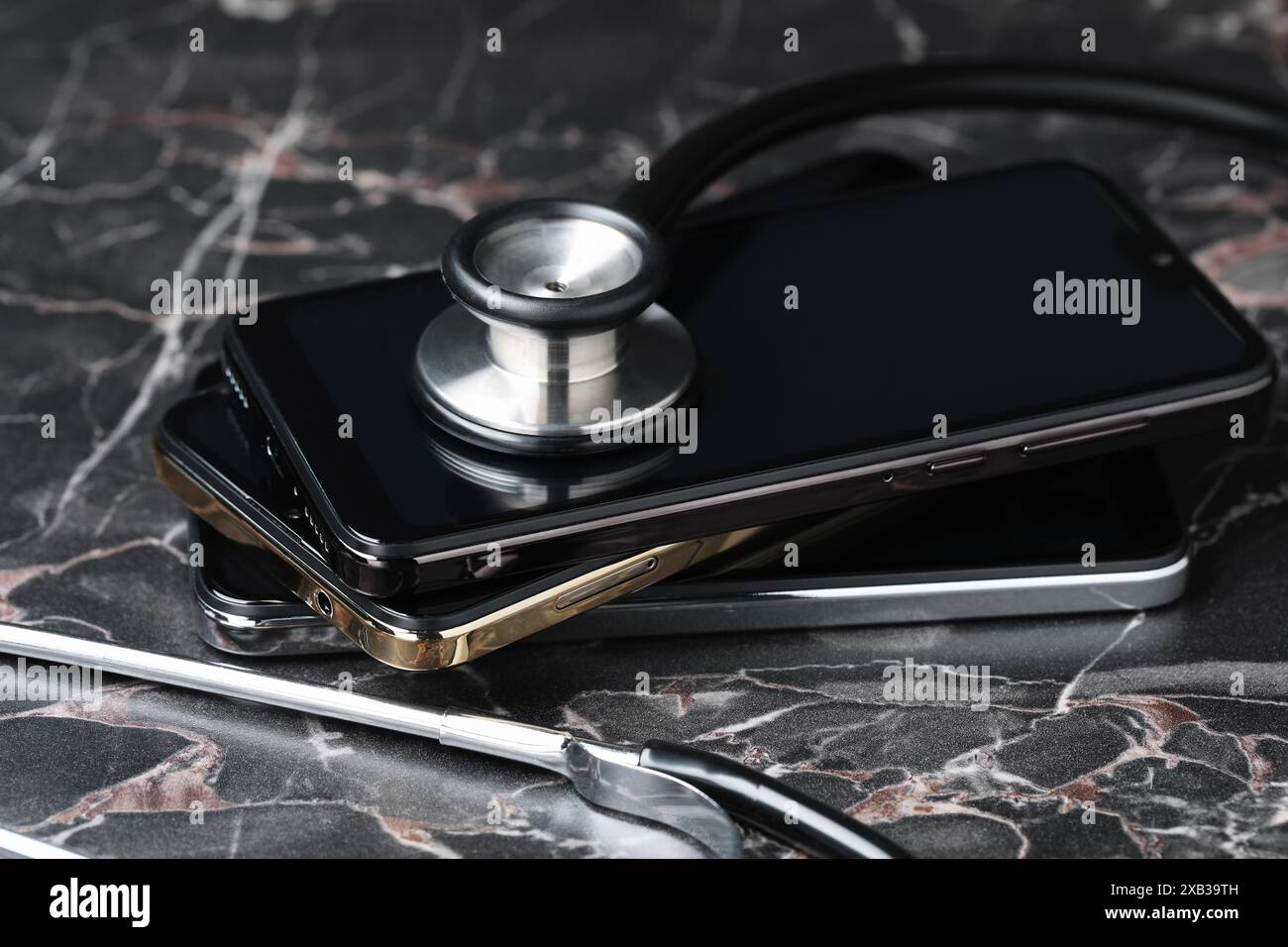 Stack of modern smartphones and stethoscope on black table Stock Photo