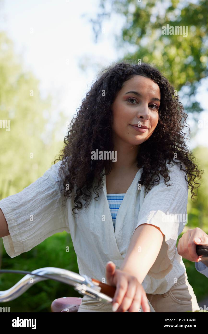 Smiling curly haired woman with bicycle Stock Photo